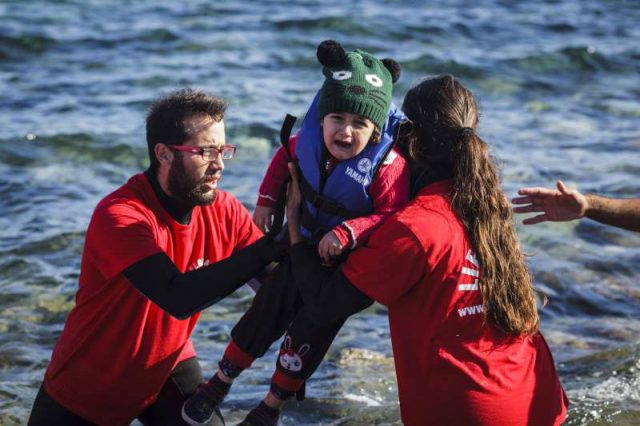 トルコからエーゲ海を渡り、レスボス島に漂着したボートから幼い子どもを抱え上げるギリシャのボランティア救助員Photo: UNHCR/Achilleas Zavallis
